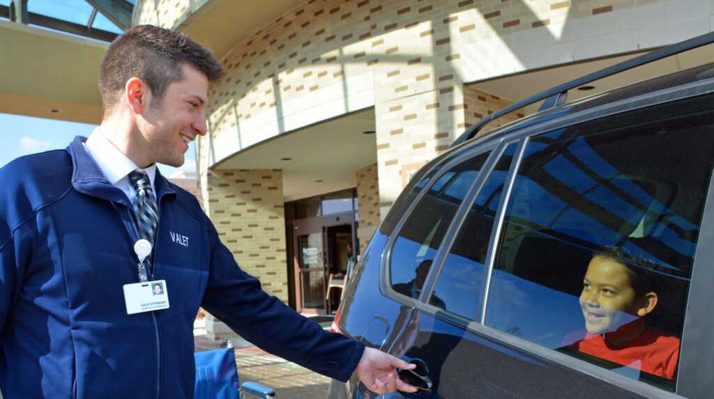 Valet attendant assisting patient at hospital entrance, demonstrating professional healthcare parking services.