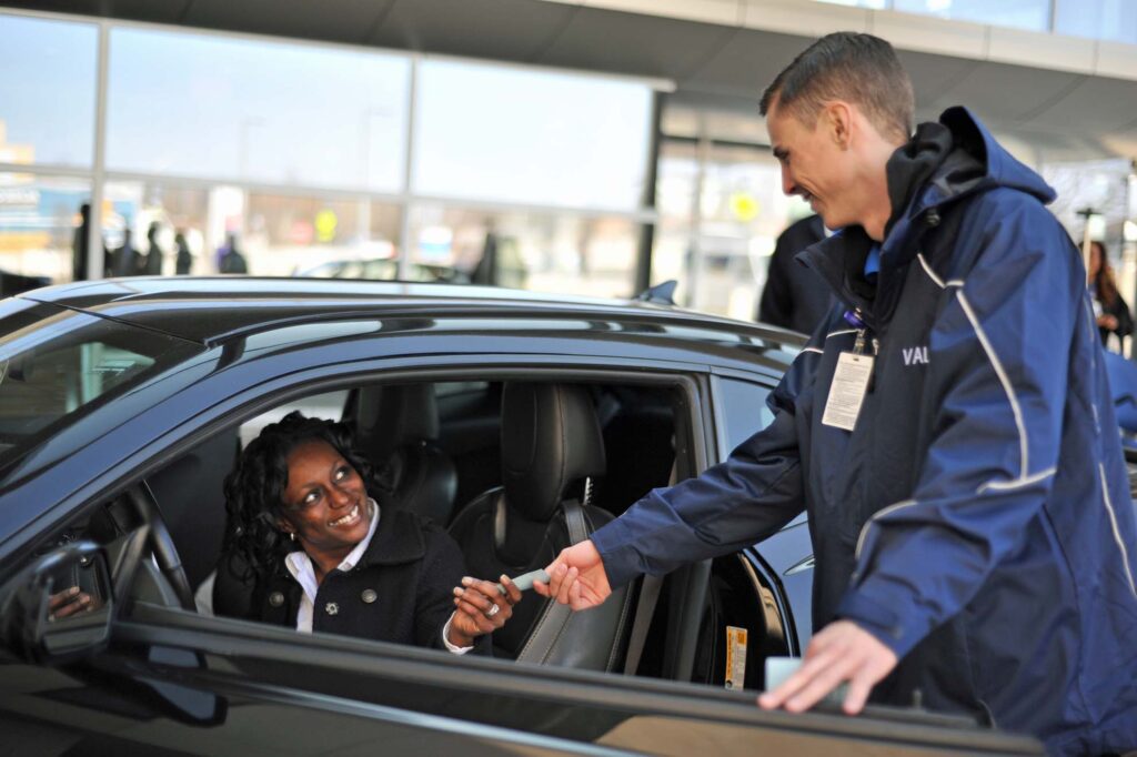 A busy hospital entrance with valet parking services in operation.