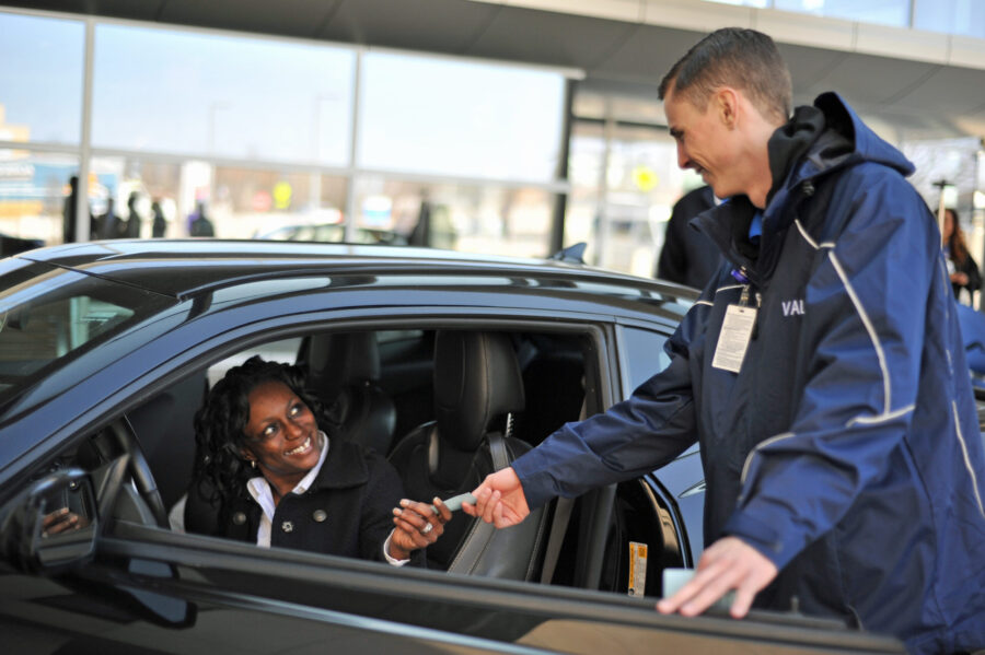 A busy hospital entrance with valet parking services in operation.